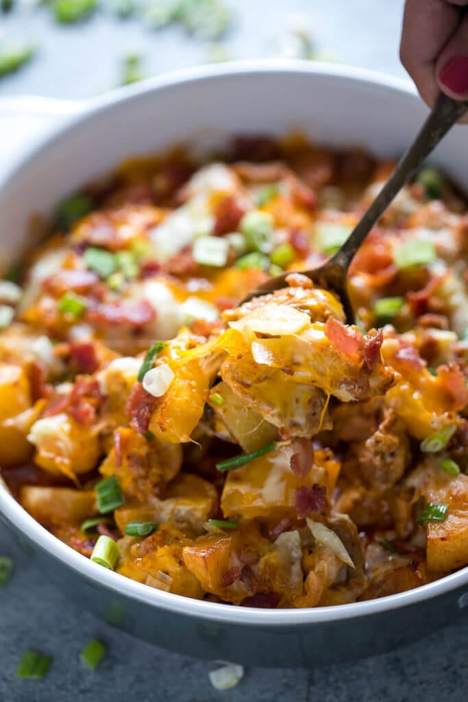 Buffalo Chicken Casserole in bowl, being scooped out with a spoon.