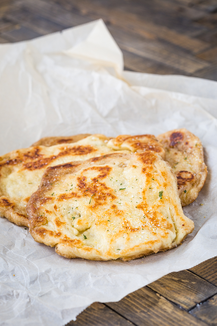 Freshly made naan bread on wax paper.