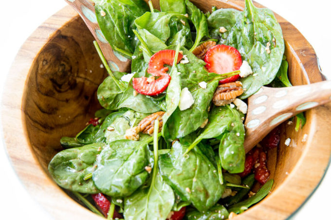 Strawberry Pecan Spinach Salad with a balsamic vinaigrette mixed together in a wooden bowl.