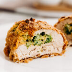 A piece of broccoli cheese stuffed chicken, cut in half, and exposing the cheese and broccoli stuffing