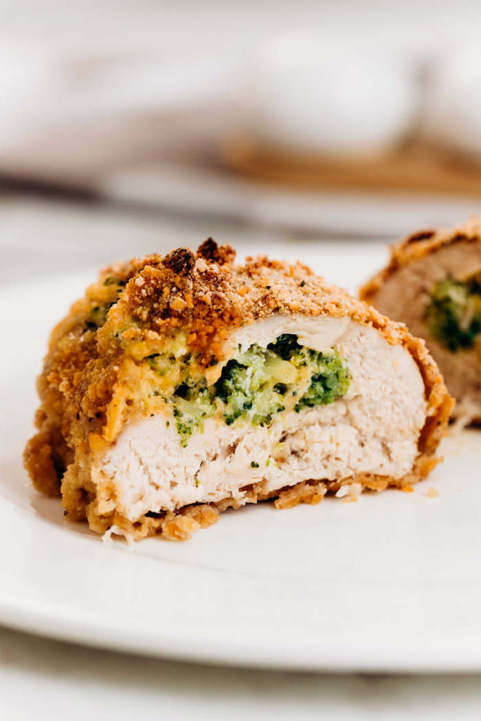 A piece of broccoli cheese stuffed chicken, cut in half, and exposing the cheese and broccoli stuffing