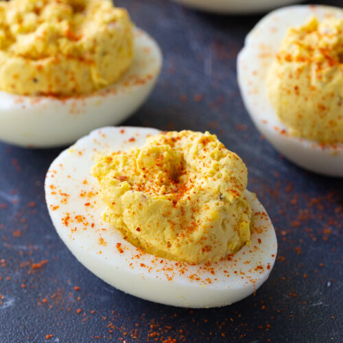 Classic deviled eggs arranged on a serving platter, filled with a creamy yolk mixture and garnished with a sprinkle of paprika – the perfect appetizer for holidays, parties, and potlucks.