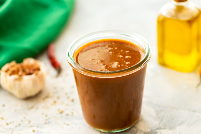 Homemade enchilada sauce in glass jar.