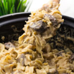 Slow cooker beef stroganoff in a crock pot with a spoon scooping some out