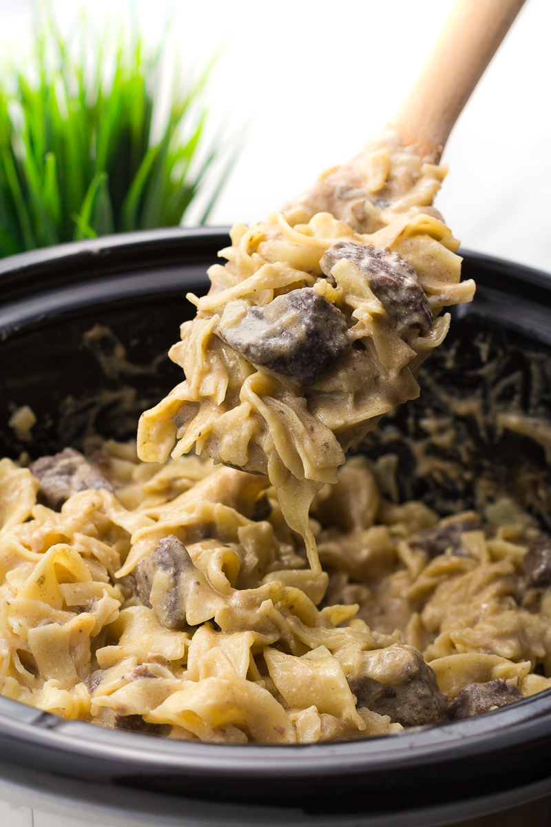 Slow cooker beef stroganoff in a crock pot with a spoon scooping some out