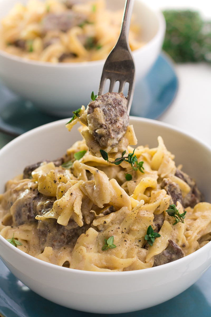 Easy slow cooker beef stroganoff in a white bowl with a fork lifting some of it out