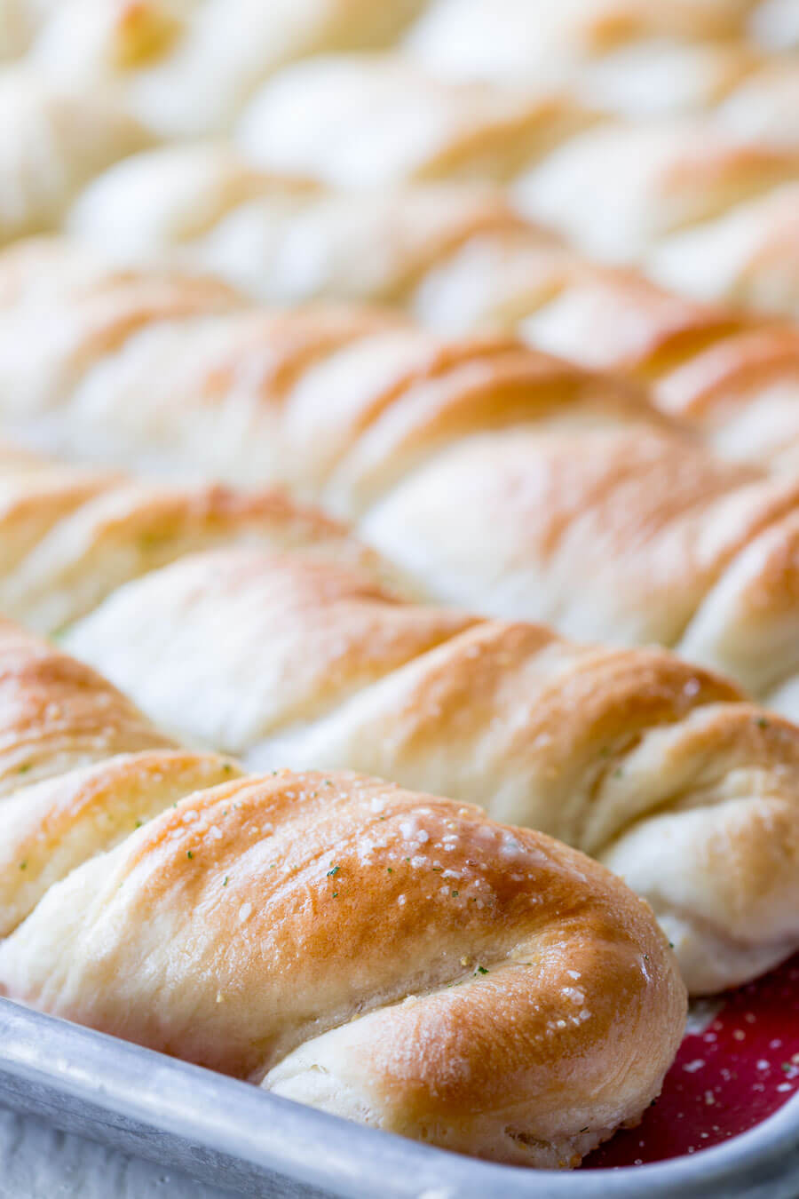 fresh homemade garlic bread twists fresh out of the oven and brushed with garlic butter on a baking sheet