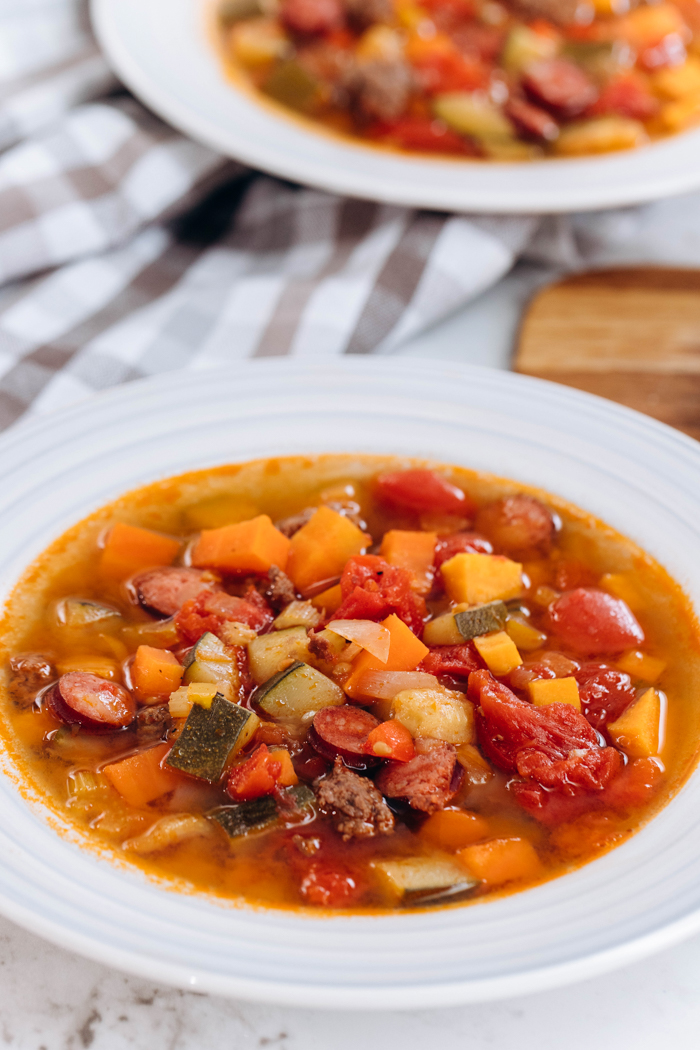 A big bowl of beef and vegetable soup, in a white bowl