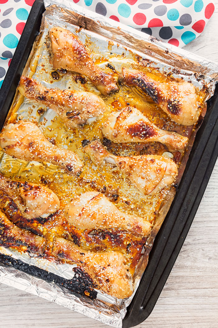 A cooking sheet with baked chicken drumsticks
