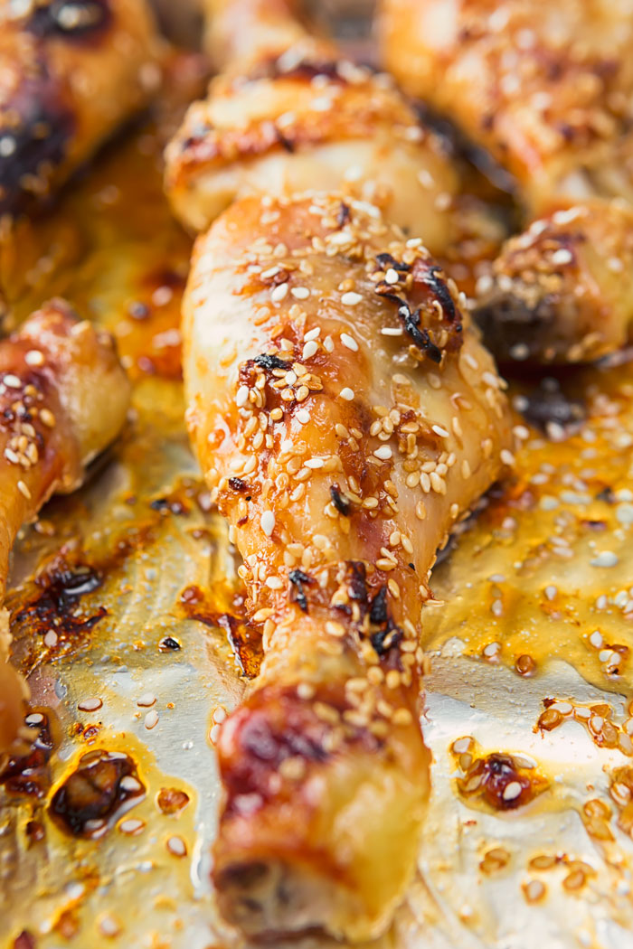 Baked chicken drumsticks on a baking sheet and sprinkled with sesame seeds. 