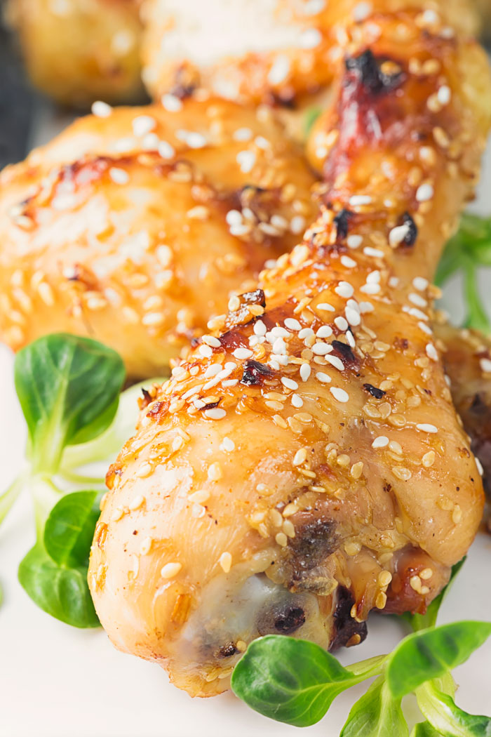 a baked sesame chicken drumstick on a platter with other drumsticks