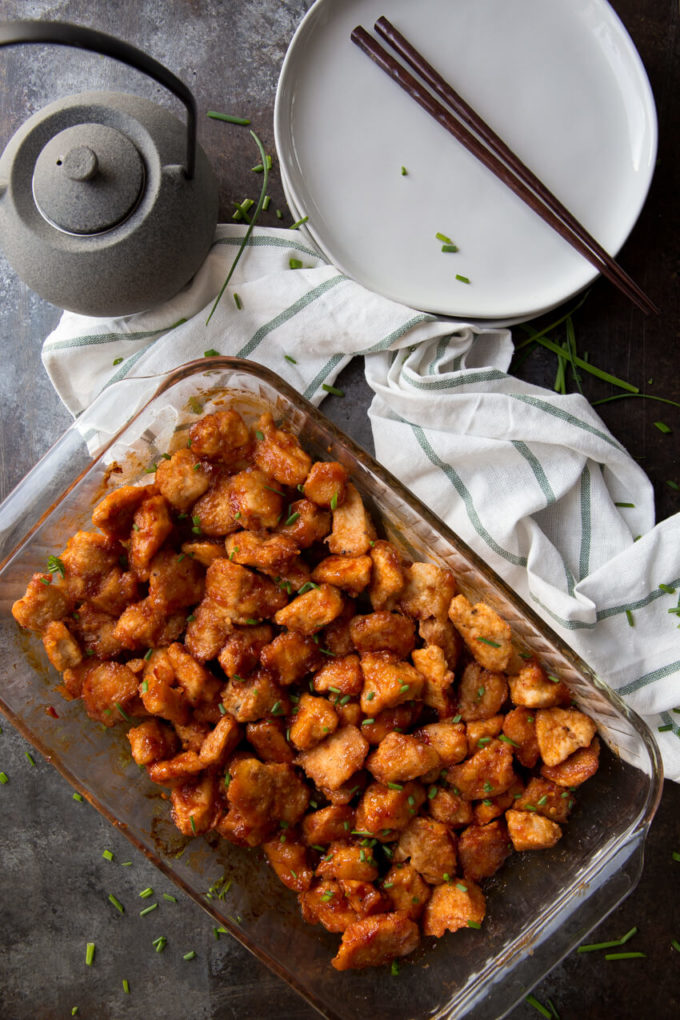 baked orange chicken in glass baking dish with towel and teapot