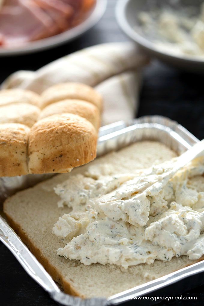 Cheesy Ham and Garlic Sandwich Bake: freshly sliced rolls filled with cream cheese in a tray in front of a bowl of cream cheese