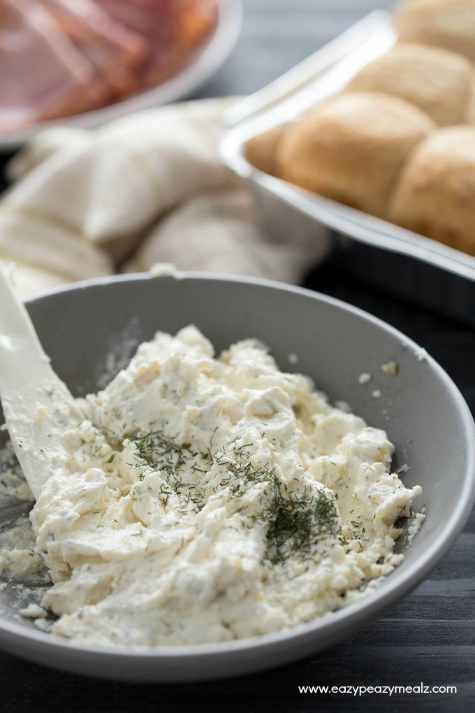 Cheesy Ham and Garlic Sandwich Bake: A gray bowl of seasoned cream cheese in front of a tray of rolls