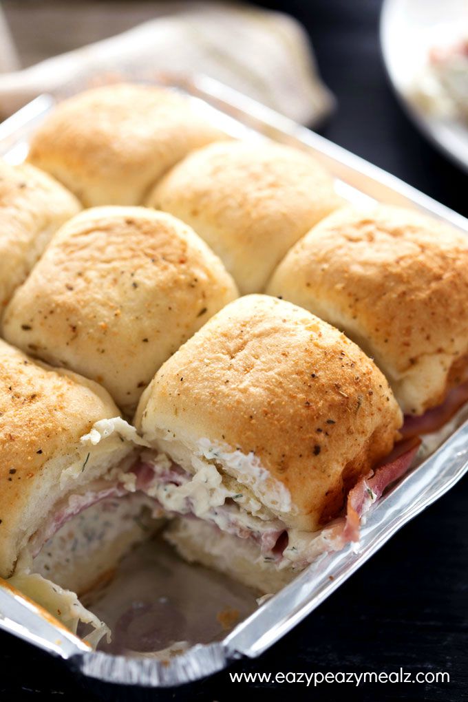 Cheesy Ham and Garlic Sandwich Bake: freshly made sandwiches sill in the tray. One sandwich missing. Baked rolls filled with cream cheese, ham, and cheese.