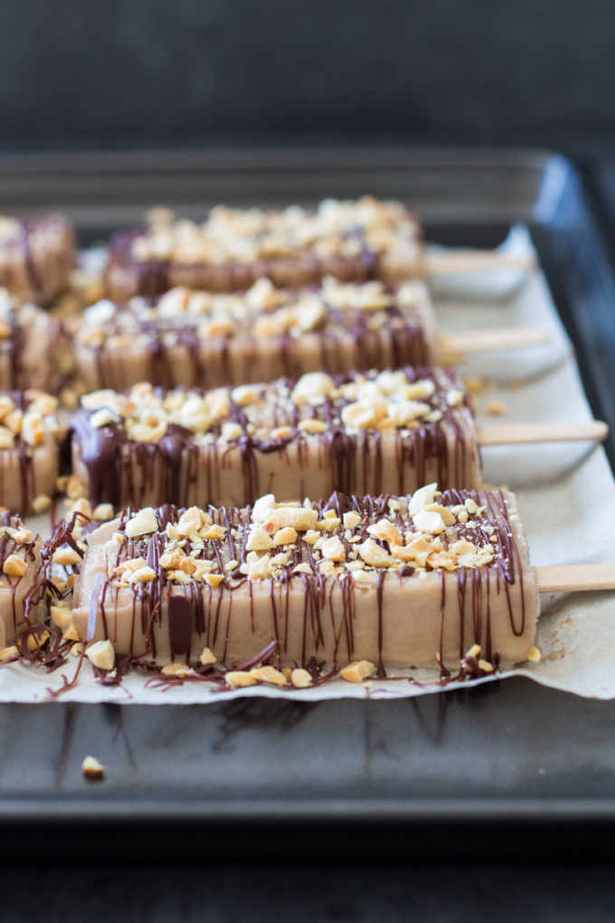Healthy yet absolutely mouthwatering Peanut Butter Banana Popsicles with chocolate and peanut pieces stuck to them. Are you drooling yet?