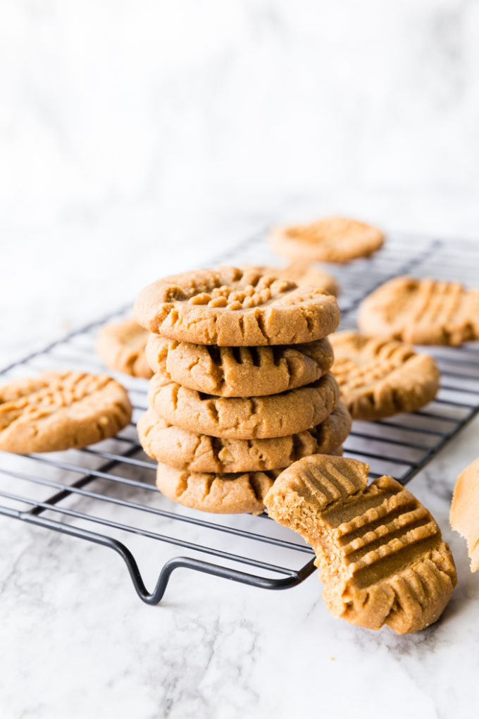 A cooling rack with a stack of delicious peanut butter cookies. 