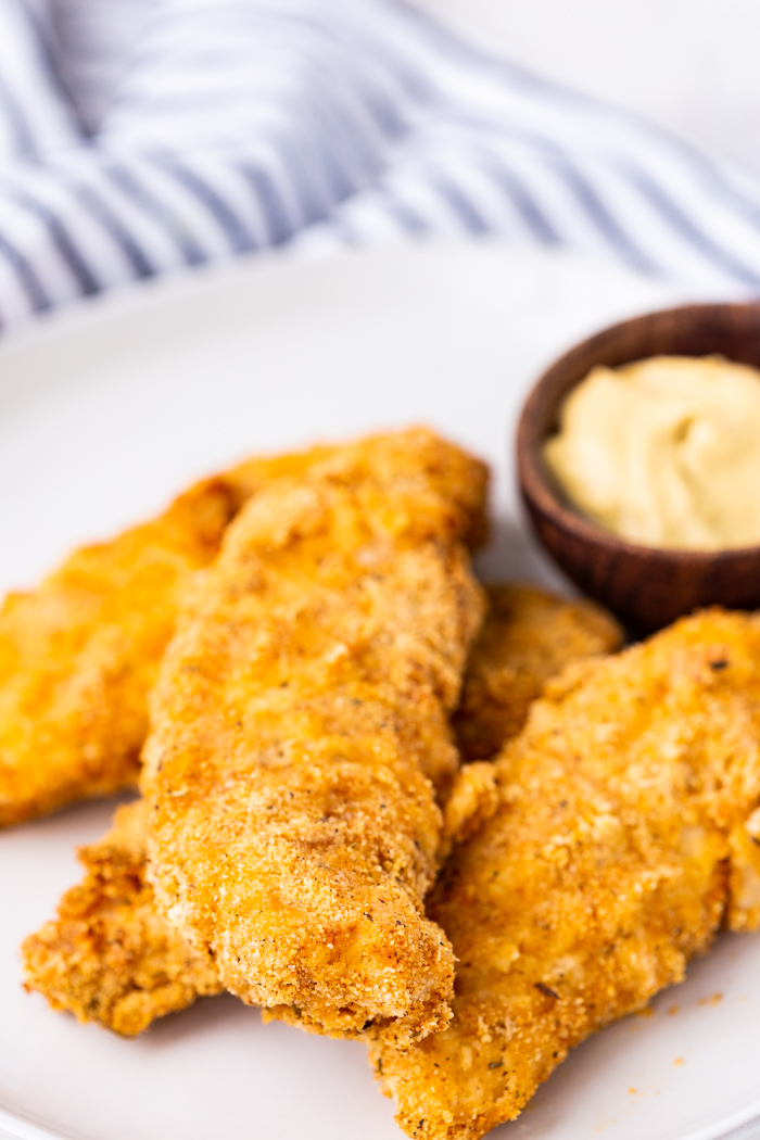 air fryer chicken cutlets on a white plate with dip in a brown bowl