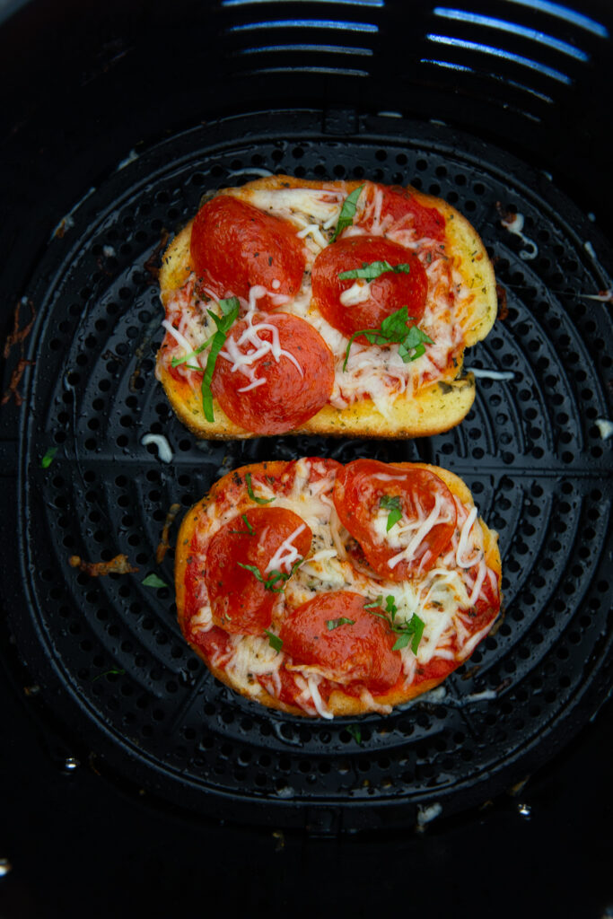 Air fryer pizza after it has been cooked and garnished with fresh basil. 