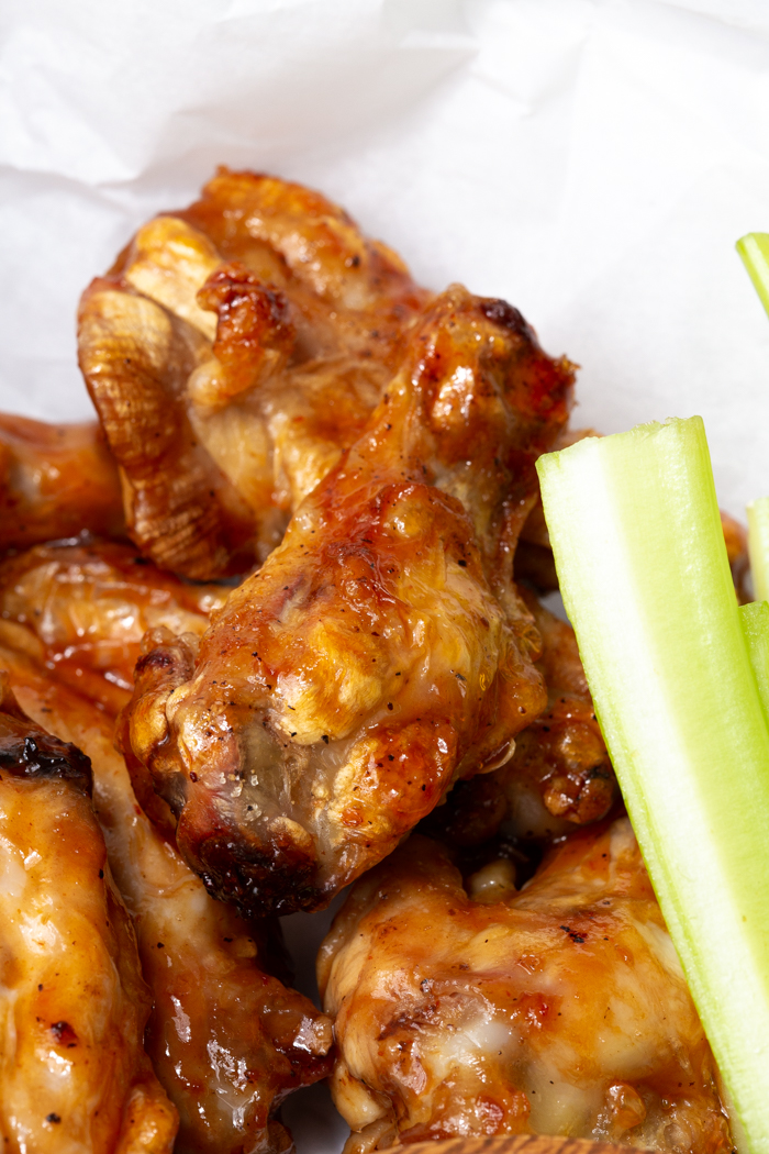 A close up of an air fryer chicken wing dipped in a great sauce