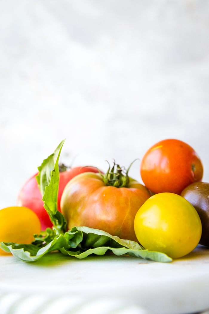 Fresh tomatoes in a pile on top of lettuce.