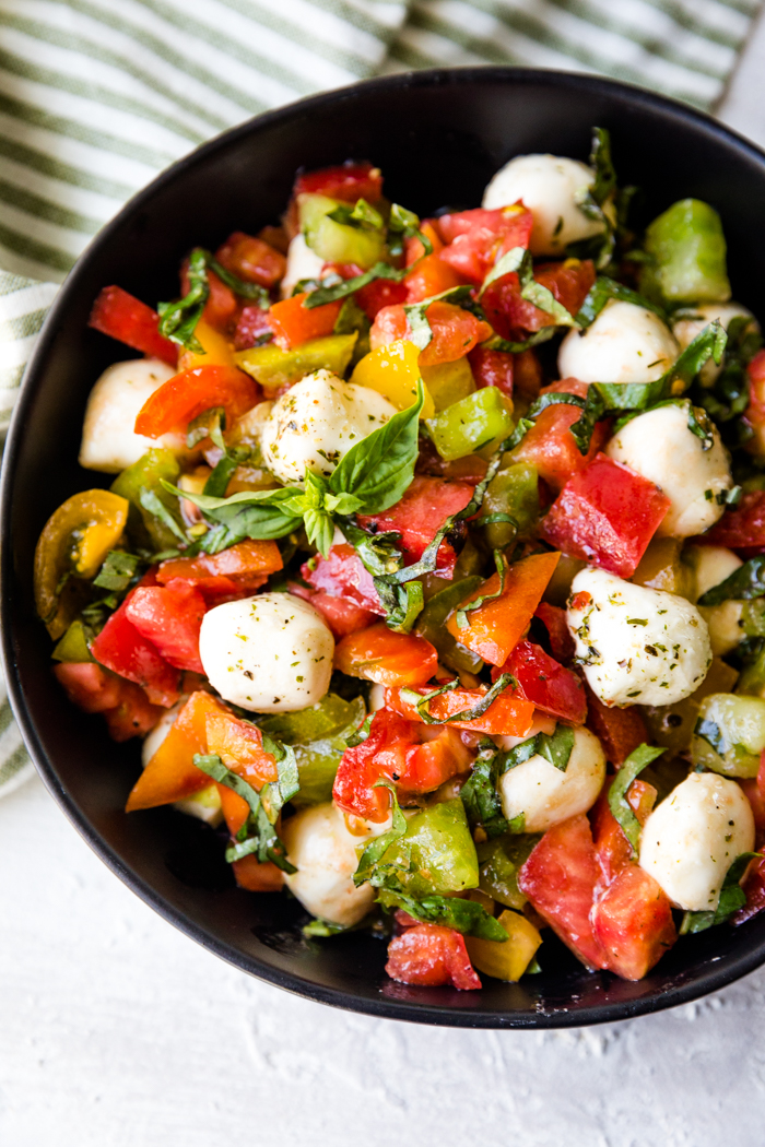 Caprese salad put together in a black bowl.