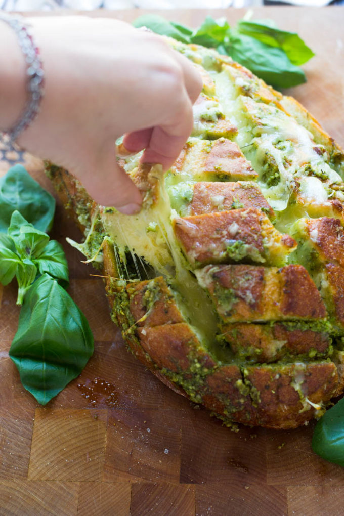 This scrumptious pull apart bread full of cheesy goodness and pesto is the ideal way to use up all that fresh basil hanging around in your garden now! Plus there has never been an easier way to make day old bread taste scrumptiously delicious!