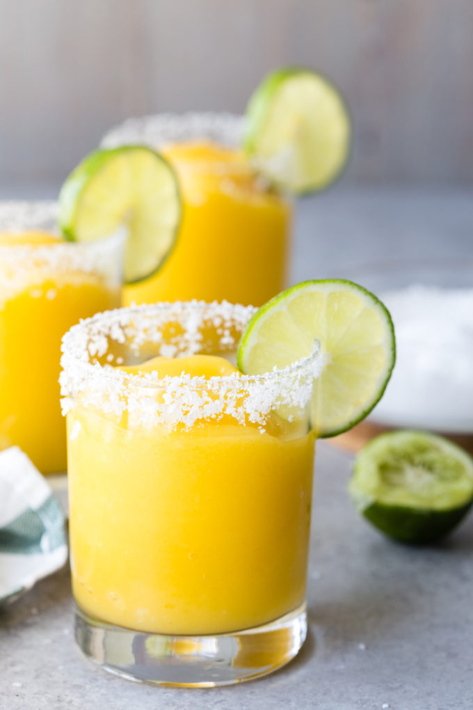 Frozen Mango Margaritas in a glass with a salted rim. 