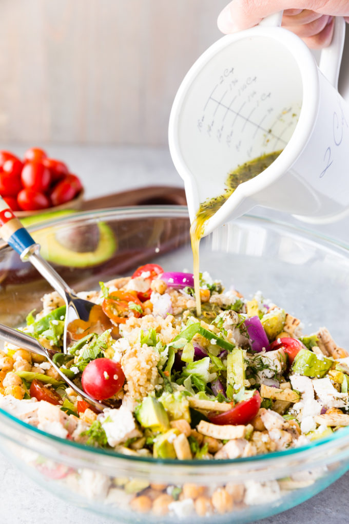 Greek Chicken Chopped Salad with a Greek dressing being poured over the top