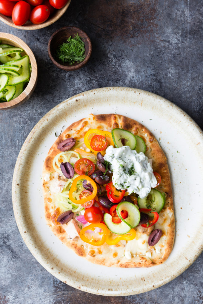 further out picture of greek chicken flatbread on a cream colored plate.