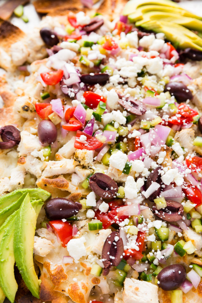 close up picture of greek chicken nachos with pita chips and toppings.