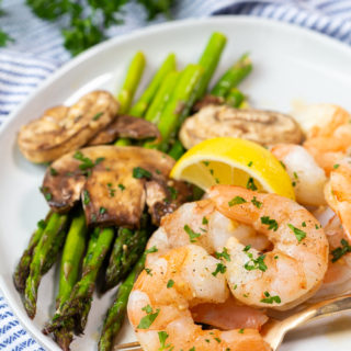 A plate with asparagus, mushrooms, and honey garlic shrimp from a low calorie sheet pan dinner