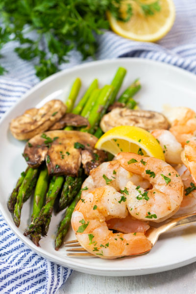 A plate with asparagus, mushrooms, and honey garlic shrimp from a low calorie sheet pan dinner