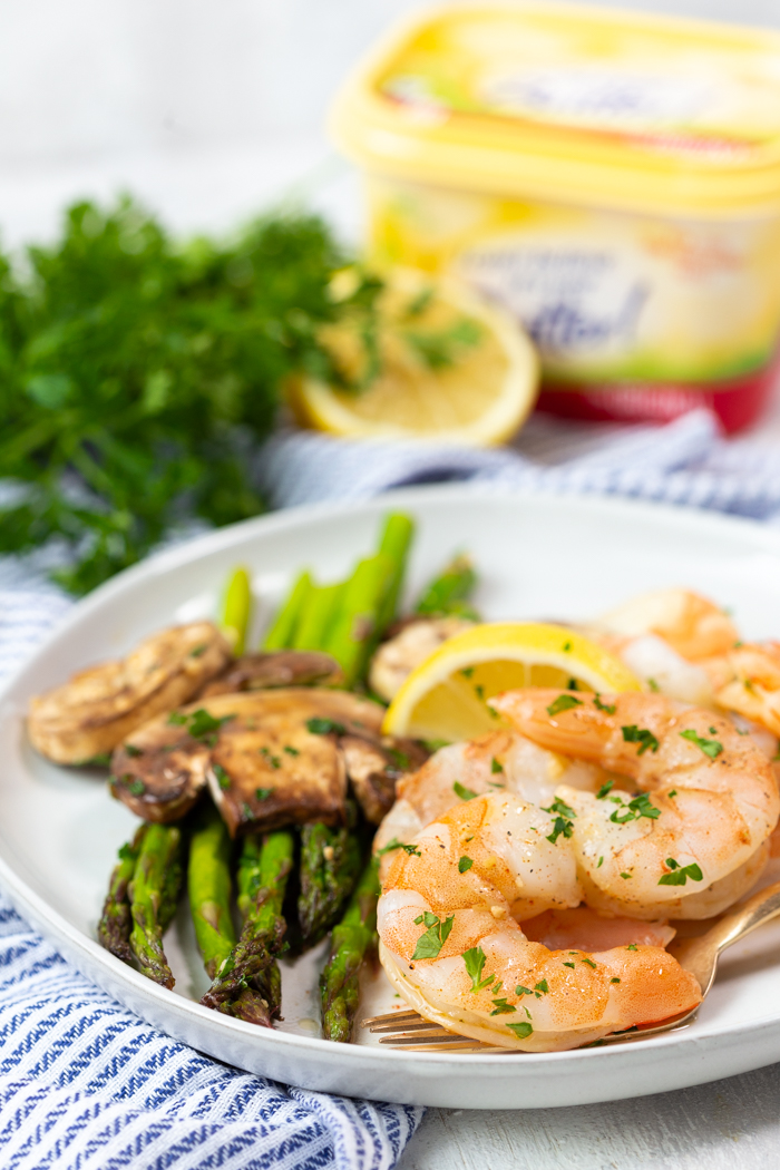 A white plate covered with honey lemon garlic shrimp and asparagus and mushrooms. 