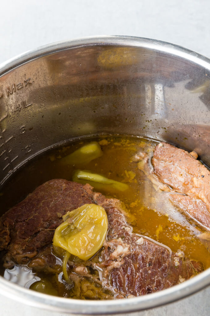chuck roast in a pot with peppercinis on top