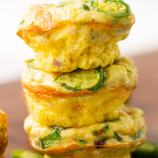 jalapeno popper egg muffins stacked in a stack of three with a few slices of jalapenos around