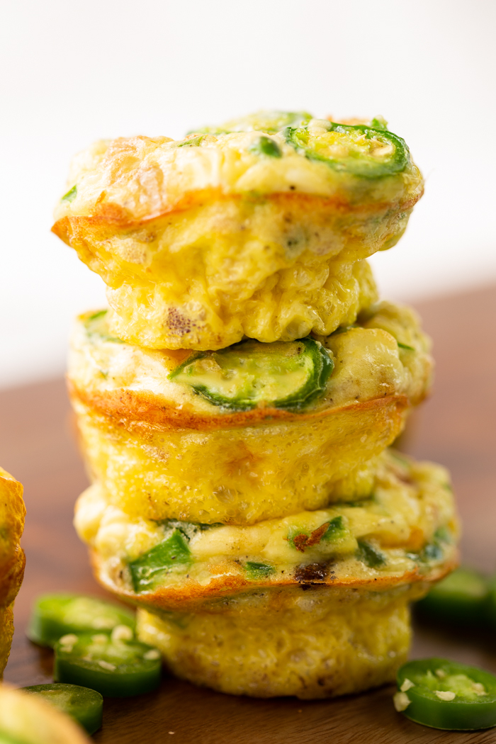 jalapeno popper egg muffins stacked in a stack of three with a few slices of jalapenos around