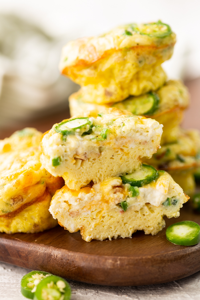 Jalapeno popper egg muffins stacked on a wooden cutting board