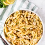Easy to make Lemon Chicken Pasta, in a big white bowl, on a green napkin, with fresh lemons