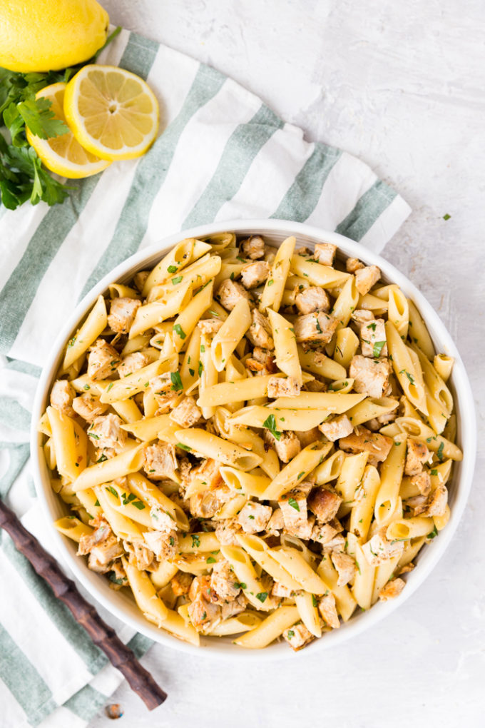 Easy to make Lemon Chicken Pasta, in a big white bowl, on a green napkin, with fresh lemons