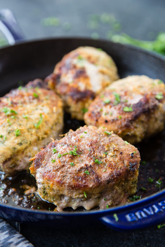 Oven baked pork chops that are breaded in Italian breadcrumbs and parmesan in a blue pan.