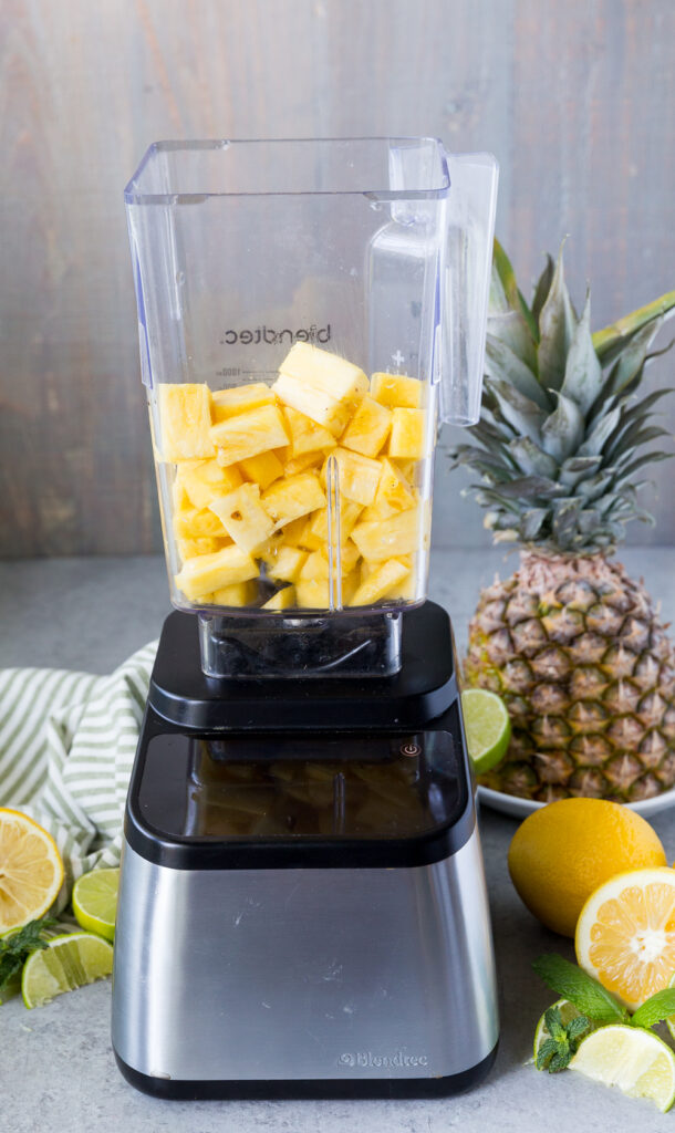 Blending pineapple and lemonade to make a refreshing pineapple lemonade.