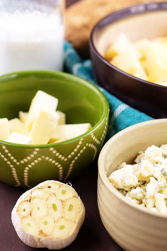 Garlic bulb, bowl of bleu cheese, bowl of butter, bowl of potatoes - ingredients for Roasted Garlic Bleu Cheese Mashed Potatoes.