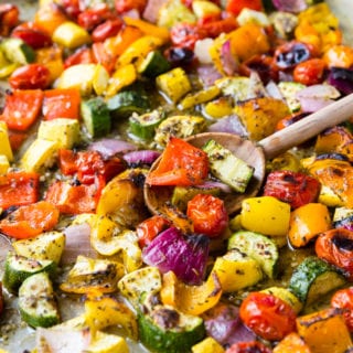 Roasted Greek Vegetables on a sheet pan with a wooden spoon.