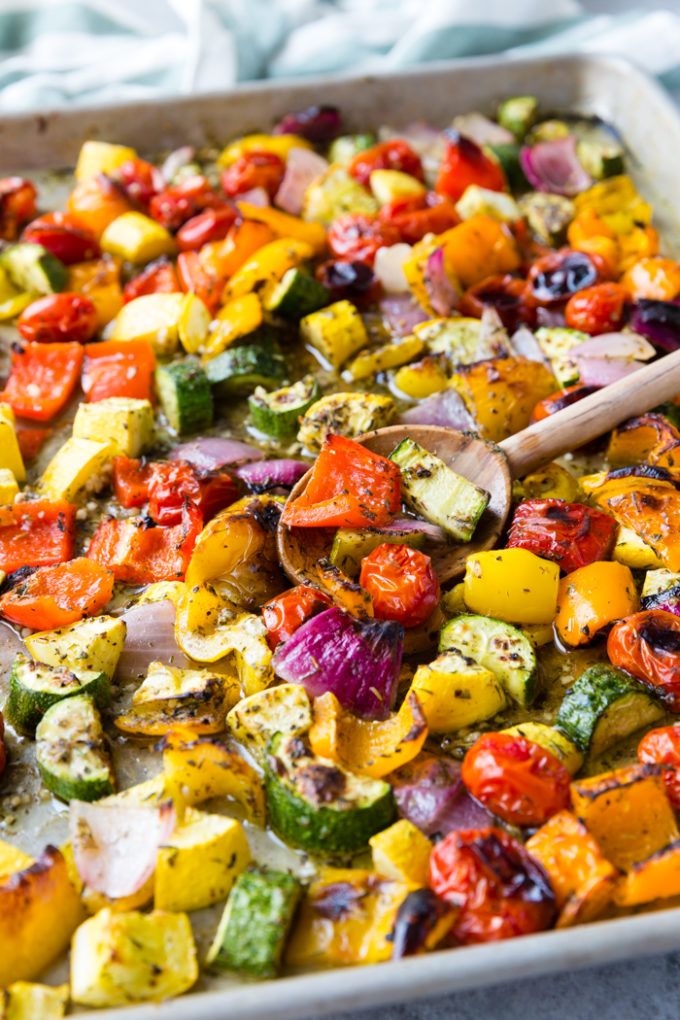 Roasted Greek Vegetables on a sheet pan with a wooden spoon. 