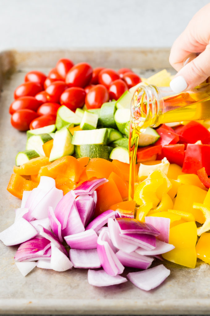 Pouring oil on top of Greek vegetables for roasting