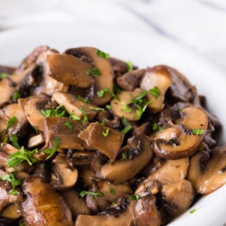 Delicious Sautéed mushrooms that are in a white dish and topped with fresh parsley