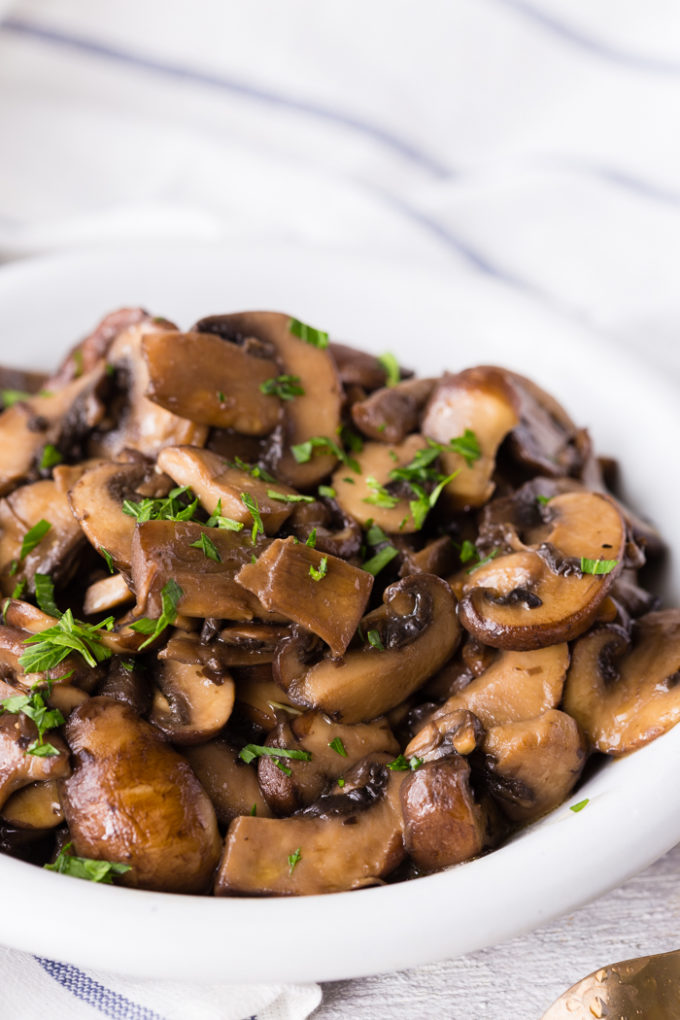 Delicious Sautéed mushrooms that are in a white dish and topped with fresh parsley