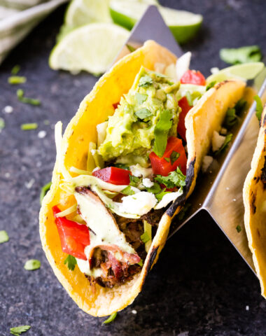 Shredded beef tacos topped with cabbage, guacamole and more