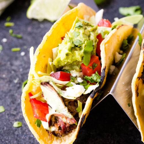 Shredded beef tacos topped with cabbage, guacamole and more